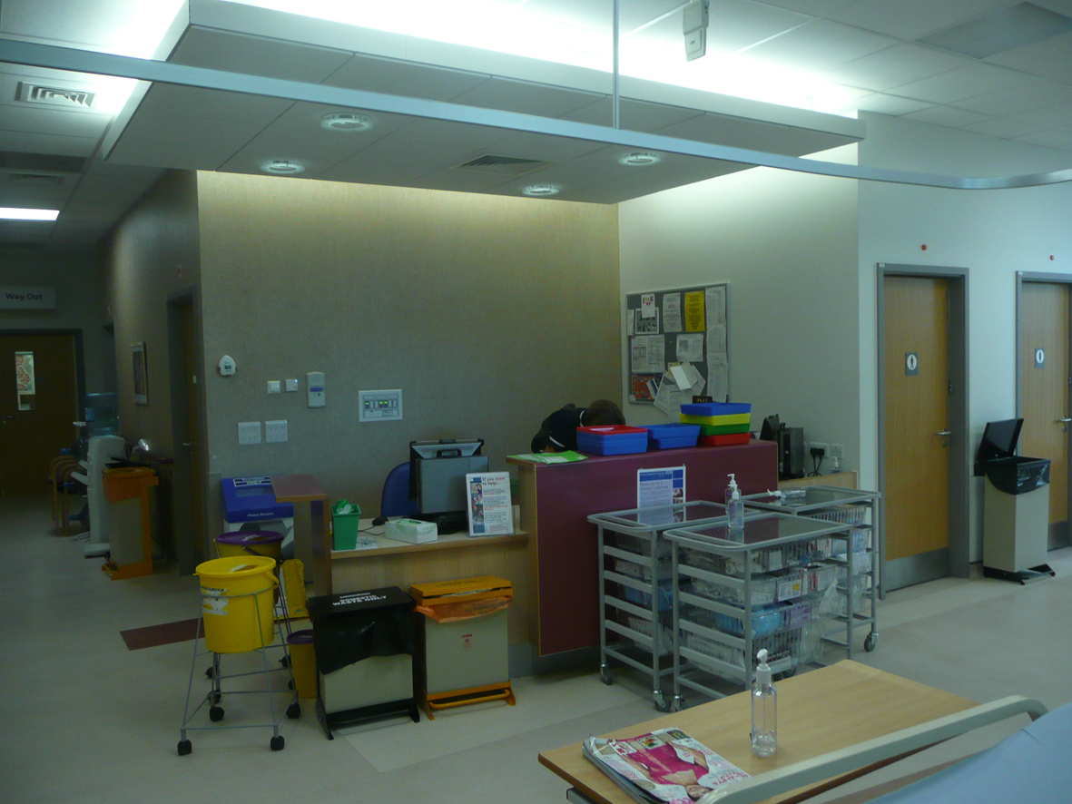 Day Treatment Unit, Nurse Station. The patients within the unit are treated in beds or chairs set out around the perimeter of the rooms, facing into the centre of the room with any windows and natural light behind them. This is a typical view of the space. 