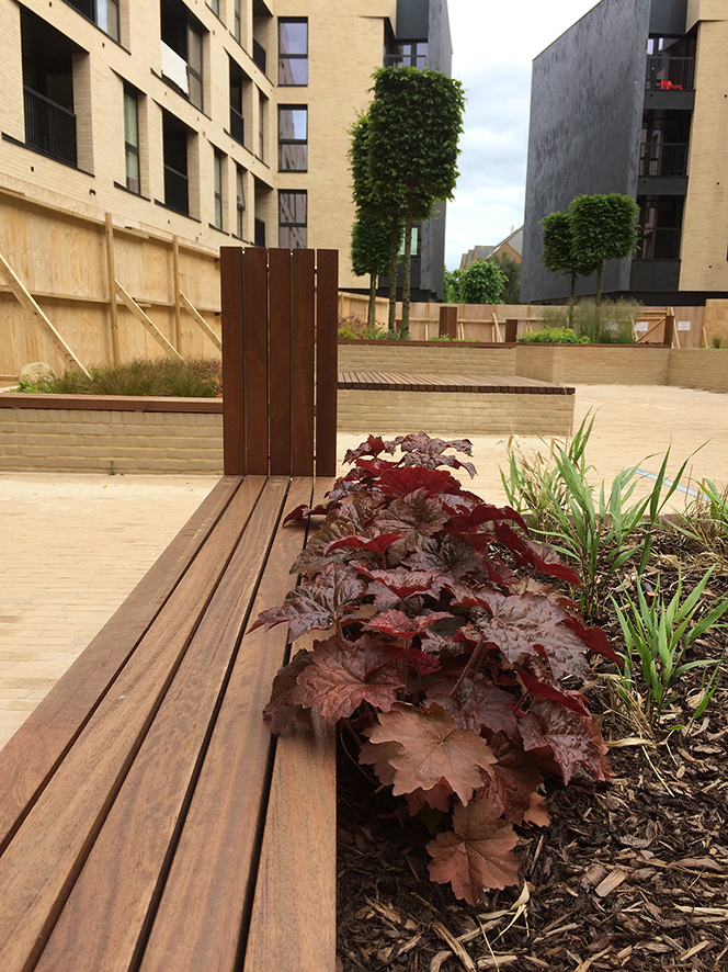 Central Chelmsford for Genesis Housing Association. Detail: Courtyard with slatted timber seating routed with text as part of the embedded public art interpretation. Image taken during installation on site. Image: Christopher Tipping